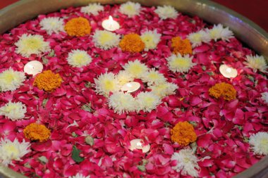 Kırmızı gül yaprakları, sarı kasımpatılar ve küçük mumların etrafına yayılmış turuncu kadife çiçekleri. Bu paspas genellikle misafirler için girişte durur..