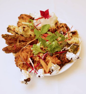 Sizzling Spice Sensation: Tandoori Chicken ve ağız sulandıran kebapların yer aldığı bir tabakta keyif çatmak, mis kokulu nane, turşu kokulu soğan halkaları ve gevrek lahana telleri ile süslenmiş, tat ve doku senfonisi vaat eden.