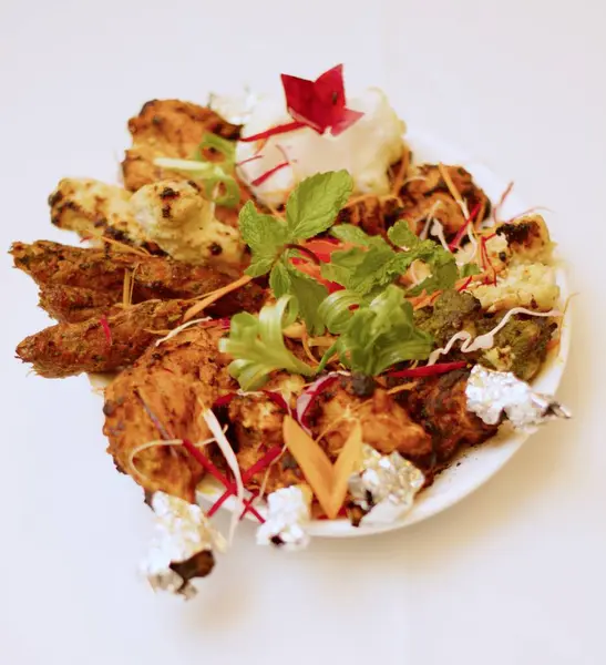 Sizzling Spice Sensation: Tandoori Chicken ve ağız sulandıran kebapların yer aldığı bir tabakta keyif çatmak, mis kokulu nane, turşu kokulu soğan halkaları ve gevrek lahana telleri ile süslenmiş, tat ve doku senfonisi vaat eden.