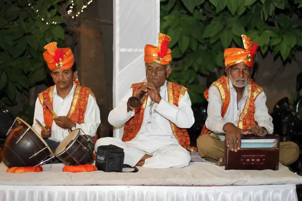 Mumbai mi? Hindistan. 18 Aralık 2014. Folk Şarkıcıları Üçlüsü canlı bir platformda sahneye çıkıyor. Renkli kıyafetlerle süslenmiş, sesleri kültürün ve mirasın duygusal hikayeleriyle yankılanıyor.. 