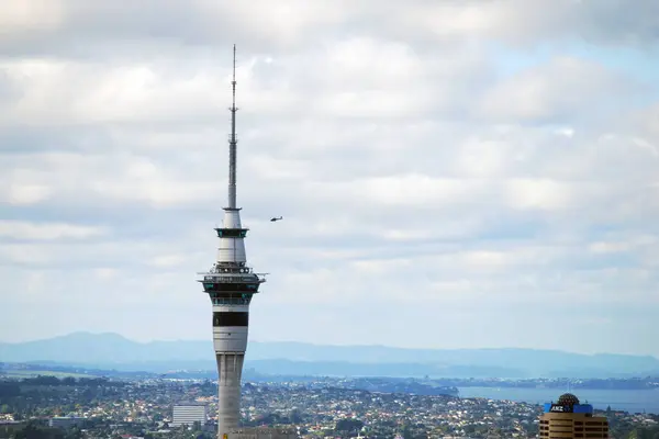 Gökyüzü Kulesi ve Helikopter Auckland 'da, Yeni Zelanda Açıklaması: Aucklands ikonik Gökyüzü Kulesi' nin yakınlarda uçan bir helikopterle dramatik bir yakın çekimi. Bu kentsel ufuk çizgisi anı statik mimari ve dinamik havacılık arasındaki zıtlığı yakalar. 