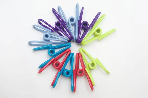 Başlık: Beyaz Arkaplanda Dairesel Desendeki Renkli Clothespinler. Temiz beyaz arkaplana karşı dairesel ve dairesel desenli olarak düzenlenmiş renkli plastik mandalların canlı tepeden aşağı görüntüsü.. 