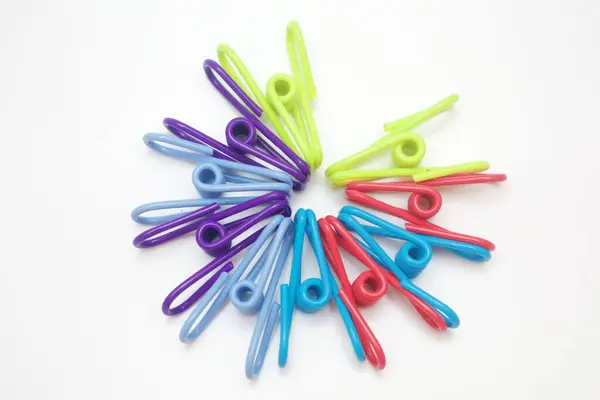Başlık: Beyaz Arkaplanda Dairesel Desendeki Renkli Clothespinler. Temiz beyaz arkaplana karşı dairesel ve dairesel desenli olarak düzenlenmiş renkli plastik mandalların canlı tepeden aşağı görüntüsü.. 