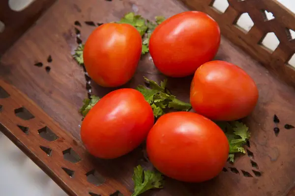 Bu durgun yaşam, günlük yemek pişirmenin kalbini oluşturan bileşenlerin sessiz güzelliğini yakalar. Dolgun domatesler süslü bir tepside yatarken kişniş filizleri Hint evlerinde tanıdık bir tazeliği yansıtıyor..