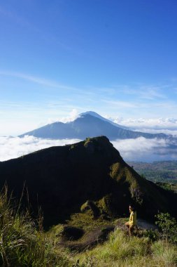 Bulut Dokuz 'un üstünde, Batur Tepesi' nde, Gökyüzü ve Bulut Denizi 'nin altında Asyalı adam gezgini