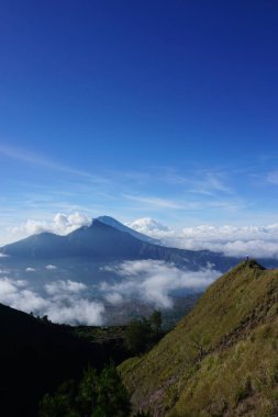 Bulut Dokuz 'un üstünde, Batur Tepesi' nde, Gökyüzü ve Bulut Denizi 'nin altında Asyalı adam gezgini