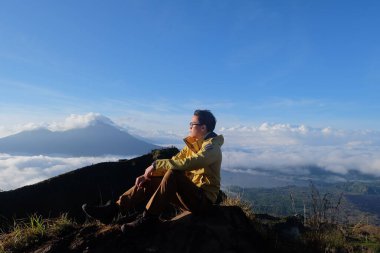 Bulut Dokuz 'un üstünde, Batur Tepesi' nde, Gökyüzü ve Bulut Denizi 'nin altında Asyalı adam gezgini