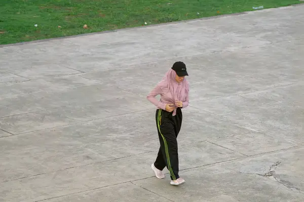 stock image Hijab Woman in Athletic Gear Enjoying a Morning Stroll in Lapangan Banteng