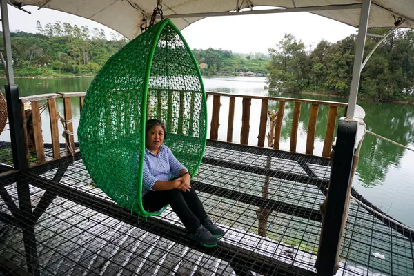 stock image Woman Relaxing in a Hanging Chair Hammock by the Lake, Nature Retreat in Lembang