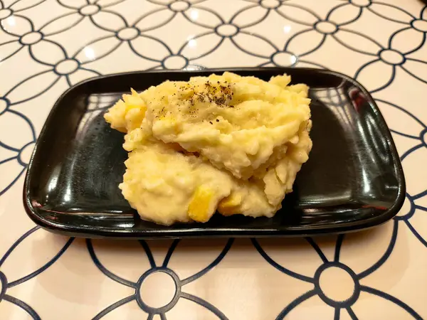 Lezzetli kremalı patates püresi taze mısır ve kara tabakta karabiber.