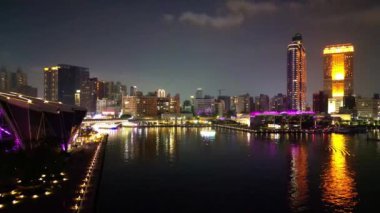 Bu hava görüntüsü Kaohsiung 'un Aşk Nehri' ni gece çekerken, aydınlık Kaohsiung Müzik Merkezi ve yakındaki iskele de dahil olmak üzere canlı bir ufuk çizgisi ile kentin modern mimari güzelliğini nehrin yansımalarına karşı sergiliyor..