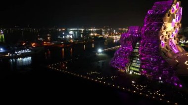 Bu canlı gece hava fotoğrafı Kaohsiung Müzik Merkezi 'ni ve bitişik iskeleyi yakalıyor ve Love River manzaralı şehir manzarasını gözler önüne seriyor..