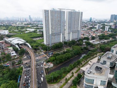 Jakarta 'nın geniş bir hava manzarası, yüksek binalar ve büyük bir tren istasyonu, şehir gelişimi ve yoğun kentsel yaşam, yerleşim yerleri ve yeşillikler sergiliyor.