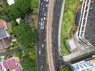 Overhead view of a busy road in Jakarta with an elevated train track running alongside, urban transport and infrastructure, city life in Indonesia's largest metropolitan area. clipart