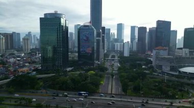 İçinden büyük bir otoyol geçen bir şehir manzarası. Binalar yüksek ve gökyüzü bulutlu