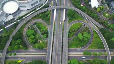 Bir sürü ağaç ve çimen olan büyük bir otoyol. Otoyol yonca şeklinde. Otoyol birçok araba ve kamyonla çok meşgul.