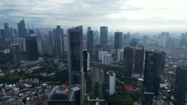 Yüksek binaları ve bulutlu gökyüzü olan bir şehir manzarası. Sahne biraz kasvetli ve bulutlu