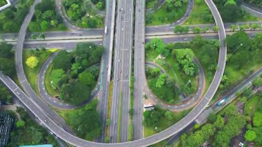 Bir sürü ağaç ve çimen olan büyük bir otoyol. Otoyol yonca şeklinde. Otoyol birçok araba ve kamyonla çok meşgul.