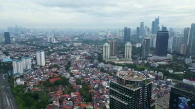 Yüksek binaları ve bulutlu gökyüzü olan bir şehir manzarası. Sahne biraz kasvetli ve bulutlu