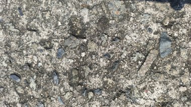 Üzerinde delikler olan gri ve beyaz yüzey yolu asfaltı. Çukur çakıl ve toprakla çevrili. Arkaplan duvar kağıdı için