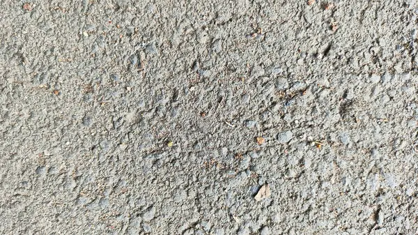 Üzerinde bir delik olan gri ve beyaz yüzey yolu asfaltı. Çukur çakıl ve toprakla çevrili. Arkaplan duvar kağıdı için