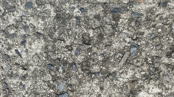 Üzerinde delikler olan gri ve beyaz yüzey yolu asfaltı. Çukur çakıl ve toprakla çevrili. Arkaplan duvar kağıdı için