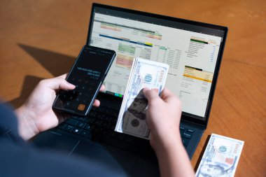 Temiz bir çalışma alanı üzerinde bir bütçe uygulaması ve hesap makinesi kullanarak kişisel finansman yöneten bir kişinin omuz üstü çekimi..