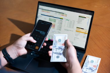 Temiz bir çalışma alanı üzerinde bir bütçe uygulaması ve hesap makinesi kullanarak kişisel finansman yöneten bir kişinin omuz üstü çekimi..