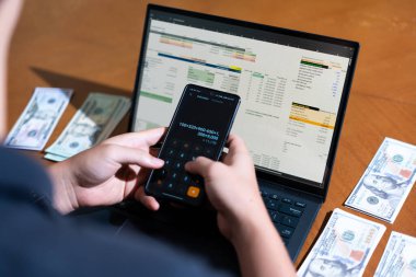 Temiz bir çalışma alanı üzerinde bütçe uygulaması tablosu kullanarak kişisel finansman yöneten bir kişinin omuz üstü çekimi.