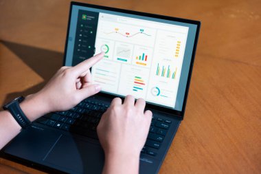 Bir kişi üzerinde grafik olan bir dizüstü bilgisayarı işaret ediyor. Grafik bir düşüş eğilimi gösteriyor, bu da satışlarda bir düşüş ya da olumsuz bir sonuç anlamına gelebilir.