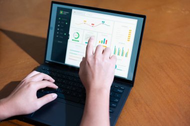 Bir iş adamının dizüstü bilgisayarda hesap tablosunu incelerken not alırken omuz üstü görüntüsü.