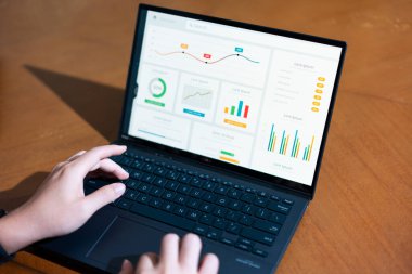 Ekranda grafik olan bir kişi dizüstü bilgisayarda yazıyor. Grafikte yükselen bir eğilim var, bu da satışlarda bir artış ya da olumlu bir sonuç anlamına gelebilir.