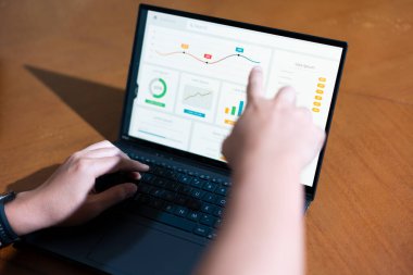 Bir iş adamının dizüstü bilgisayarda hesap tablosunu incelerken not alırken omuz üstü görüntüsü.