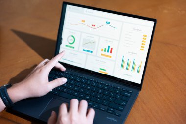 Birisi ekranında grafik olan bir dizüstü bilgisayar kullanıyor. Grafikte bir düşüş eğilimi var, bu da satışlarda bir düşüş ya da olumsuz bir sonuç olabilir. Bu kişi muhtemelen verileri analiz ediyor.