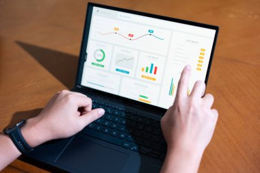 Bir iş adamının dizüstü bilgisayarda hesap tablosunu incelerken not alırken omuz üstü görüntüsü.