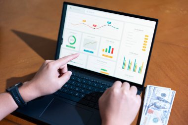 Bir kişi üzerinde grafik olan bir dizüstü bilgisayarı işaret ediyor. Grafik yukarı ve sağa doğru giden bir doğru gösteriyor.