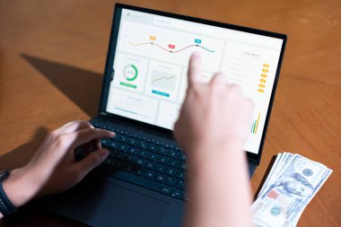 Bir iş adamının dizüstü bilgisayarda hesap tablosunu incelerken not alırken omuz üstü görüntüsü.