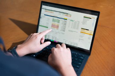 Temiz bir çalışma alanı üzerinde bütçe uygulaması tablosu kullanarak kişisel finansman yöneten bir kişinin omuz üstü çekimi.