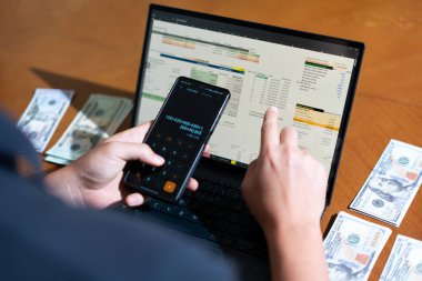 Temiz bir çalışma alanı üzerinde bütçe uygulaması tablosu kullanarak kişisel finansman yöneten bir kişinin omuz üstü çekimi.