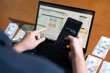 Temiz bir çalışma alanı üzerinde bütçe uygulaması tablosu kullanarak kişisel finansman yöneten bir kişinin omuz üstü çekimi.