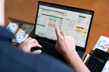 Temiz bir çalışma alanı üzerinde bir bütçe uygulaması ve hesap makinesi kullanarak kişisel finansman yöneten bir kişinin omuz üstü çekimi..