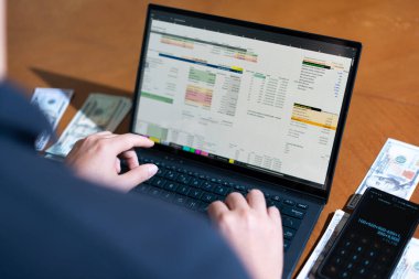 Temiz bir çalışma alanı üzerinde bütçe uygulaması tablosu kullanarak kişisel finansman yöneten bir kişinin omuz üstü çekimi.