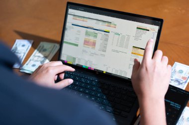 Temiz bir çalışma alanı üzerinde bir bütçe uygulaması ve hesap makinesi kullanarak kişisel finansman yöneten bir kişinin omuz üstü çekimi..