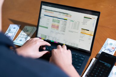 Temiz bir çalışma alanı üzerinde bir bütçe uygulaması ve hesap makinesi kullanarak kişisel finansman yöneten bir kişinin omuz üstü çekimi..