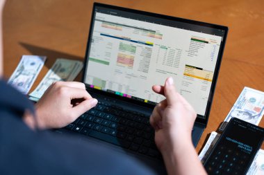 Temiz bir çalışma alanı üzerinde bir bütçe uygulaması ve hesap makinesi kullanarak kişisel finansman yöneten bir kişinin omuz üstü çekimi..