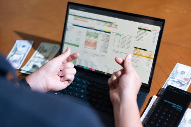 Temiz bir çalışma alanı üzerinde bir bütçe uygulaması ve hesap makinesi kullanarak kişisel finansman yöneten bir kişinin omuz üstü çekimi..