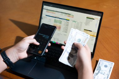 Temiz bir çalışma alanı üzerinde bir bütçe uygulaması ve hesap makinesi kullanarak kişisel finansman yöneten bir kişinin omuz üstü çekimi..