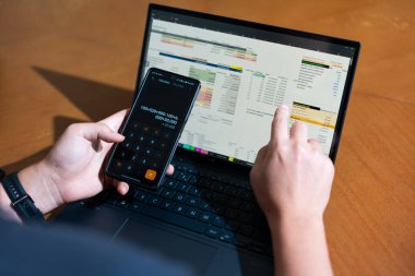 Temiz bir çalışma alanı üzerinde bütçe uygulaması tablosu kullanarak kişisel finansman yöneten bir kişinin omuz üstü çekimi.