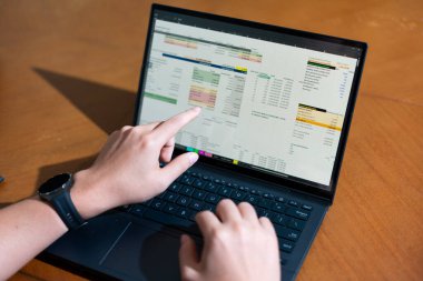 Temiz bir çalışma alanı üzerinde bütçe uygulaması tablosu kullanarak kişisel finansman yöneten bir kişinin omuz üstü çekimi.