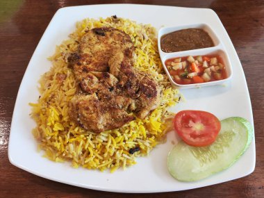 Bir tabak yemek, bir parça tavuk ve yanında sebze. Tabak ahşap bir masaya konmuş.